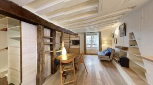 Vue panoramique d'un studio parisien rénové avec cuisine ouverte et salon lumineux, illustrant l'optimisation de l'espace pour une estimation immobilière réussie dans le 5e arrondissement