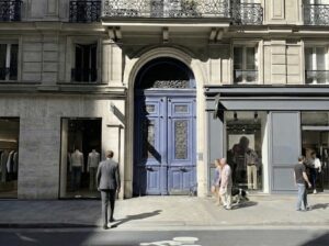 Julien Benyamin, expert immobilier chez ULYS Immobilier, marchant vers l'entrée monumentale d'un immeuble haussmannien à Paris pour une expertise de valorisation.