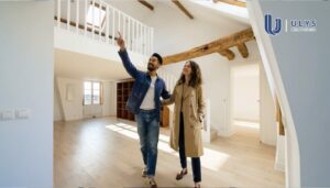 Couple visitant un appartement lumineux avec mezzanine et poutres apparentes.